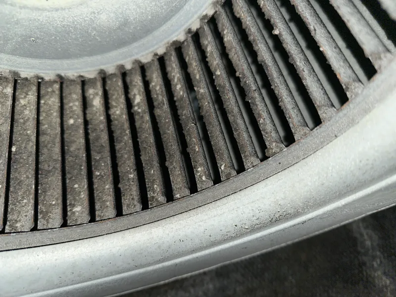 Dust caked between the blades of an AC blower wheel before cleaning