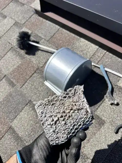 Chimney cap and cleaning tools on roof during service