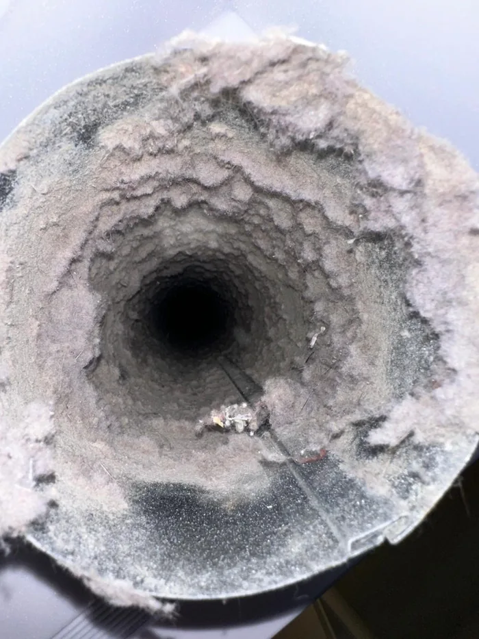 Clogged dryer vent packed with lint before cleaning